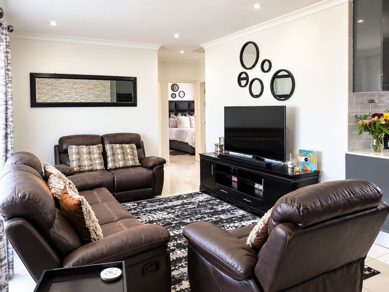 A well-maintained living room featuring tiled flooring, recessed downlighting, and neutral wall finishes, providing a comfortable and bright space.