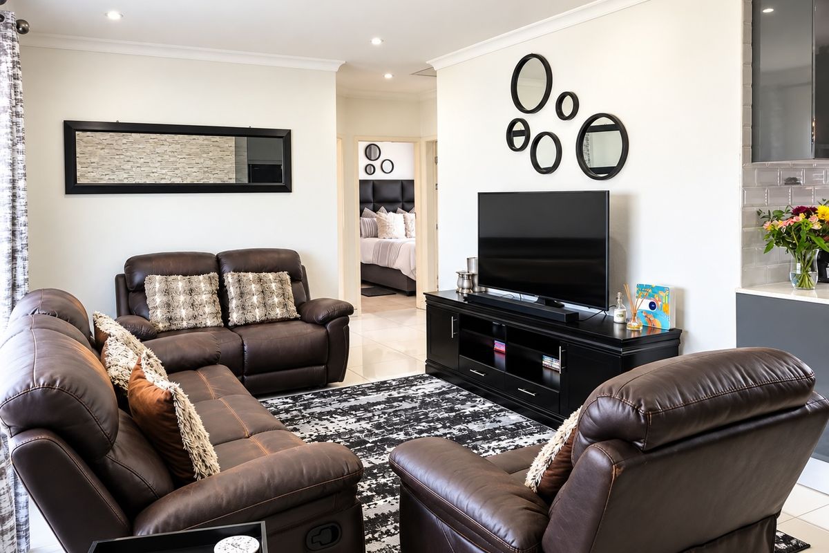 A well-maintained living room featuring tiled flooring, recessed downlighting, and neutral wall finishes, providing a comfortable and bright space.