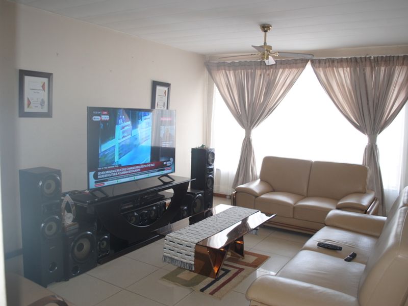 A living room featuring tiled flooring and a ceiling fan, providing a functional and comfortable space for relaxation.