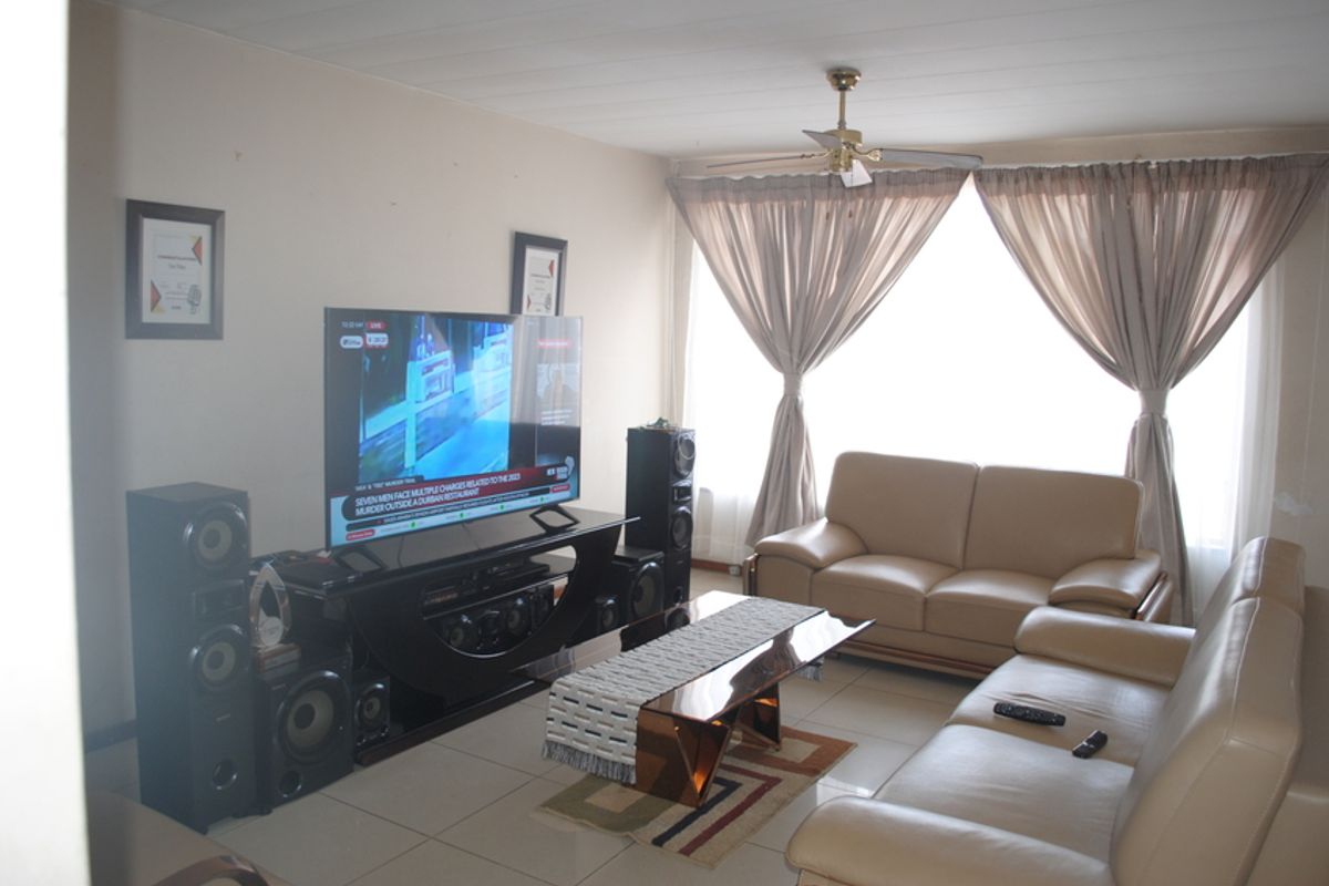 A living room featuring tiled flooring and a ceiling fan, providing a functional and comfortable space for relaxation.