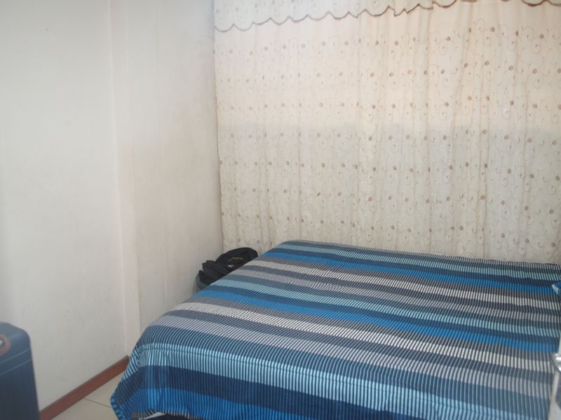 A compact bedroom featuring tiled flooring and neutral wall finishes, providing a functional space for a single or double bed setup.