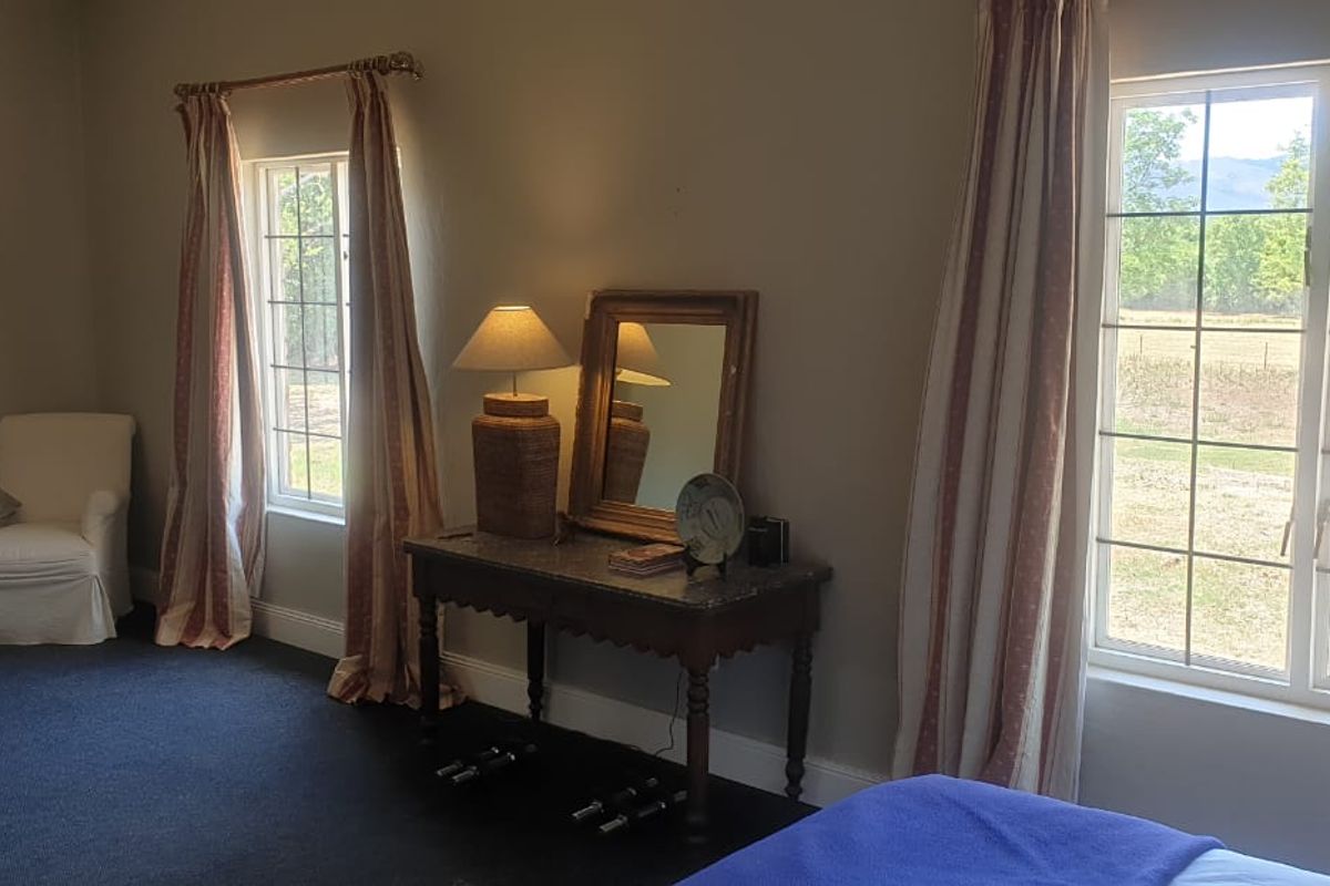 A spacious bedroom featuring large grid-pattern windows that provide ample natural light and views of the surrounding farm landscape.