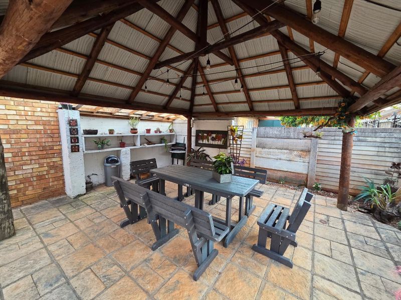 Covered outdoor patio area featuring a timber-framed roof, built-in shelving, and paved flooring, ideal for alfresco dining and outdoor entertainment.