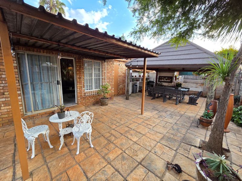 A spacious outdoor patio area featuring paved flooring, a covered seating section, and an adjacent gazebo, providing a functional space for outdoor entertaining.