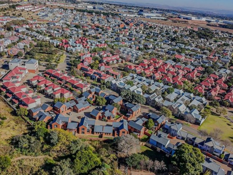 An aerial view of a residential estate featuring multiple housing units, paved road networks, and surrounding landscaped green spaces.