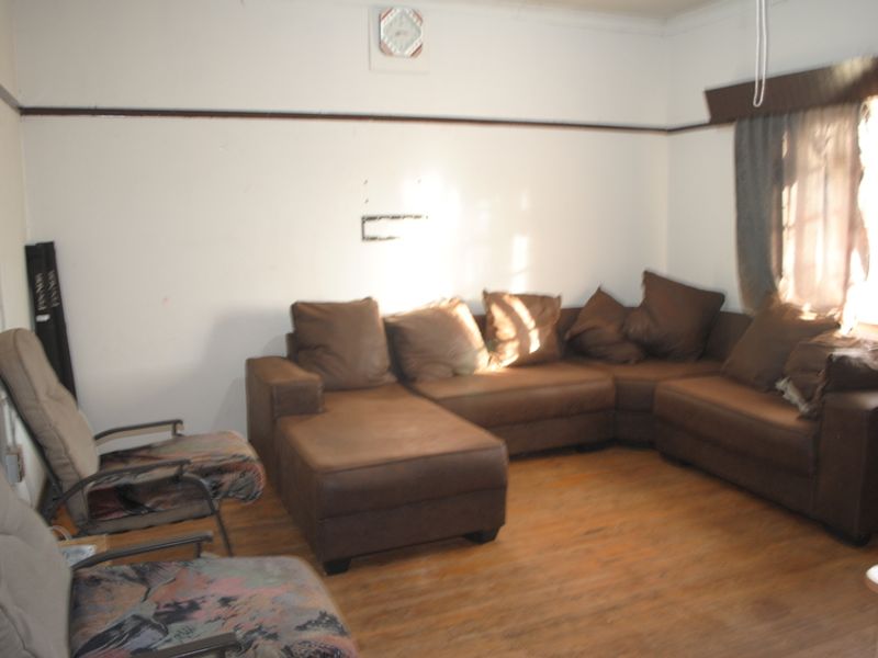 A living room featuring timber flooring, picture rails, and traditional cornicing, requiring cosmetic updates to improve its overall presentation.
