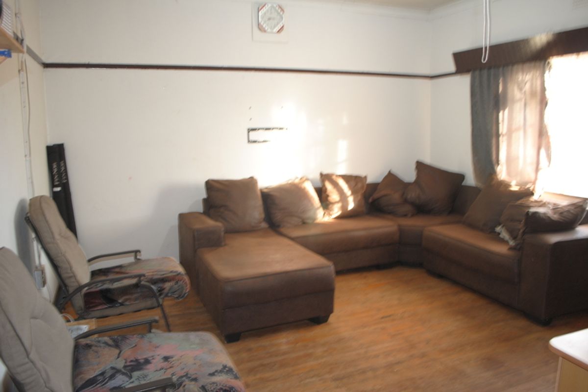 A living room featuring timber flooring, picture rails, and traditional cornicing, requiring cosmetic updates to improve its overall presentation.