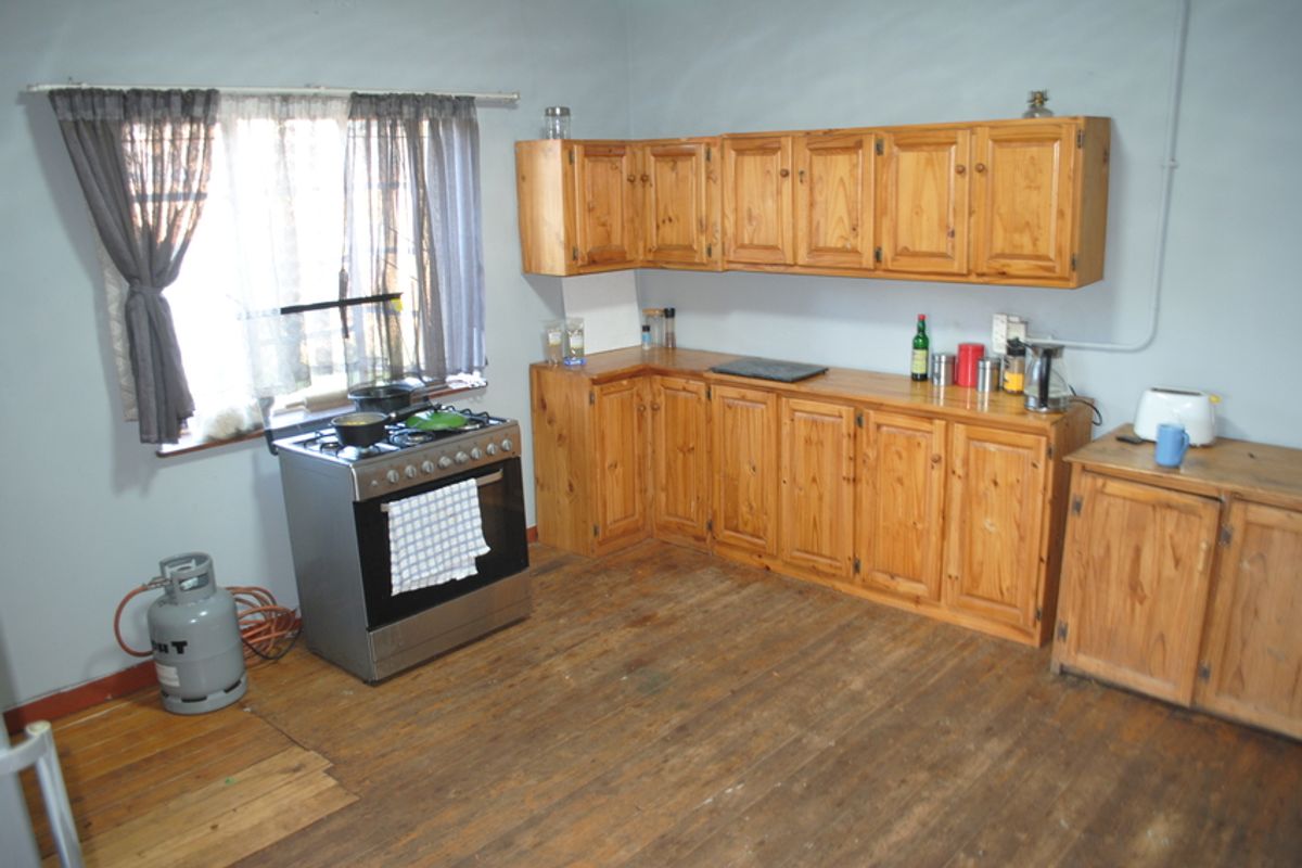 A functional kitchen featuring timber cabinetry, a gas stove, and original timber flooring, offering potential for modernization and aesthetic updates.