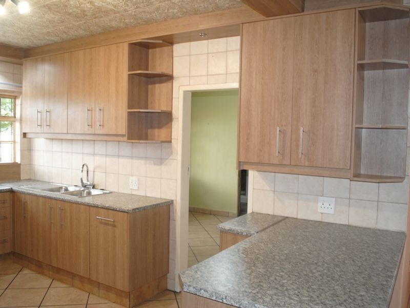 A functional kitchen featuring laminate cabinetry, stone-look countertops, tiled backsplash, and tiled flooring, offering a clean and practical layout.