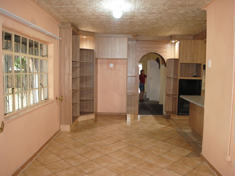 Open plan living area featuring tiled flooring, built-in cabinetry, and an arched doorway leading to adjacent rooms.