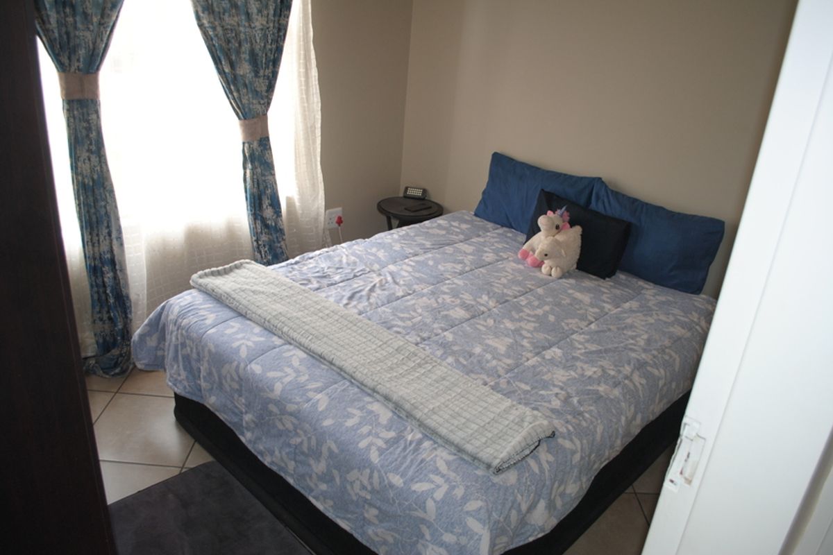 A compact bedroom featuring tiled flooring and natural light through a window with installed curtain rails.