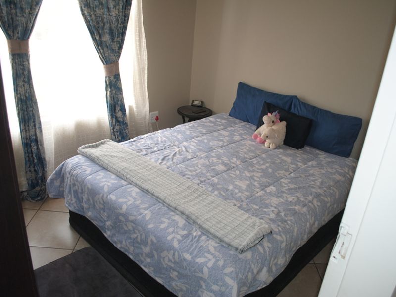 A compact bedroom featuring tiled flooring and natural light through a window with installed curtain rails.