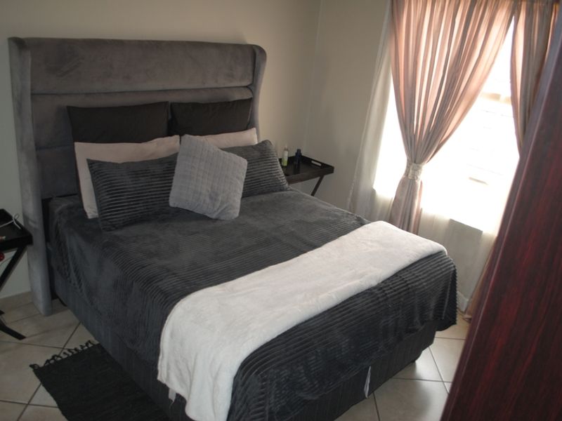 A bedroom featuring tiled flooring and window treatments, providing a functional and comfortable sleeping space.