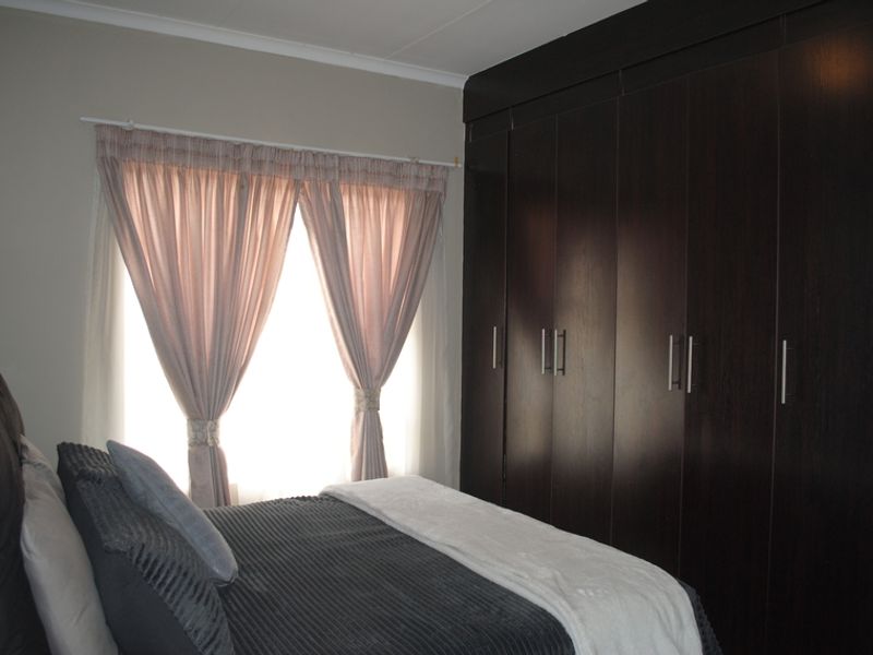 A well-maintained bedroom featuring dark wood built-in cupboards and neutral wall finishes, providing ample storage space.
