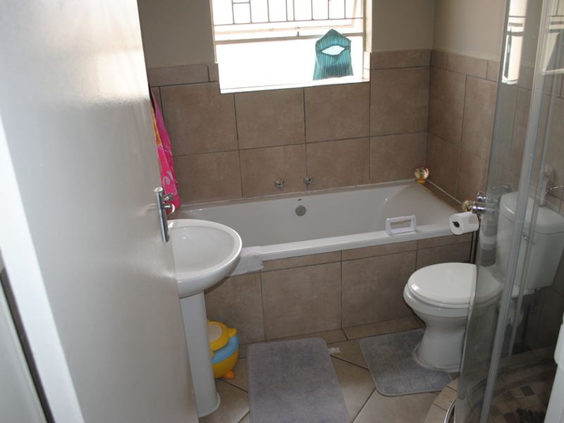 A functional bathroom featuring a bathtub, pedestal basin, toilet, and a separate shower enclosure with tiled finishes throughout.