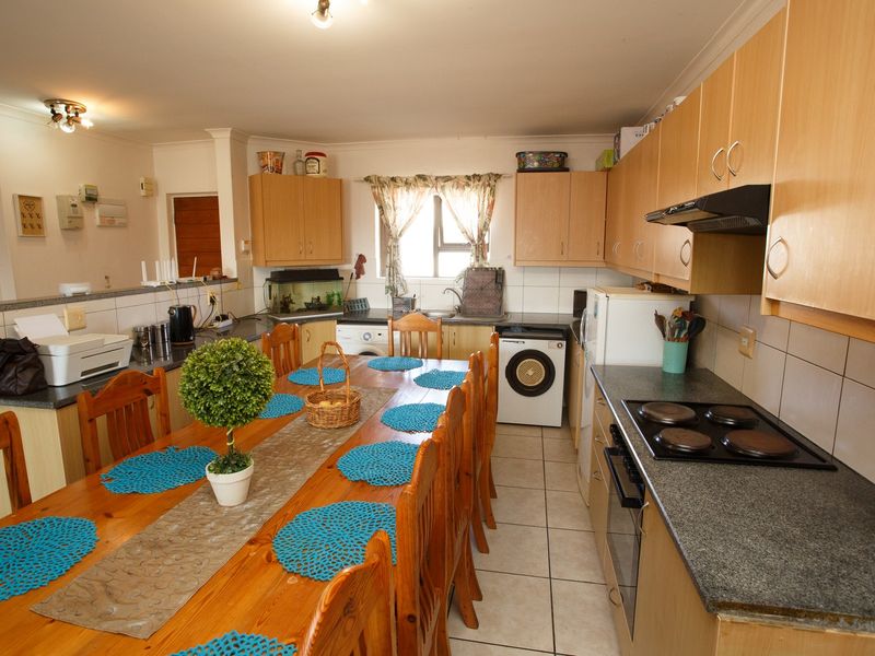 Open-plan kitchen and dining area featuring wooden cabinetry, tiled flooring, and integrated cooking appliances, offering a functional layout for daily living.