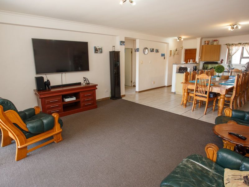 Open-plan living and dining area featuring a combination of carpeted and tiled flooring, with an adjacent kitchen space.