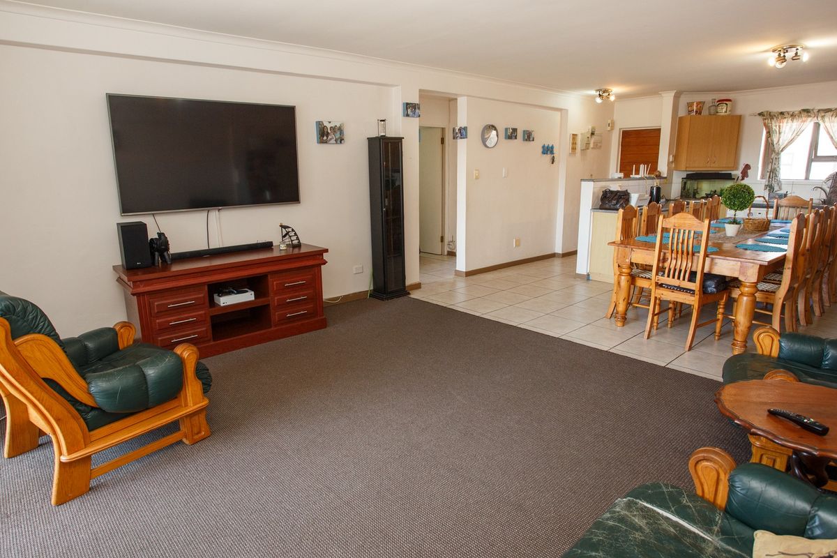 Open-plan living and dining area featuring a combination of carpeted and tiled flooring, with an adjacent kitchen space.