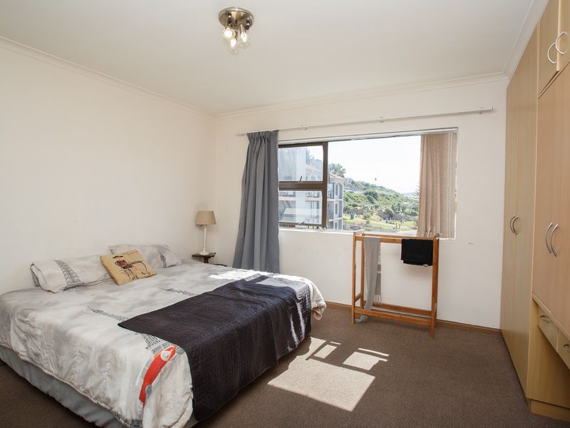 A functional bedroom featuring built-in cupboards, carpeted flooring, and a window with natural light and exterior views.
