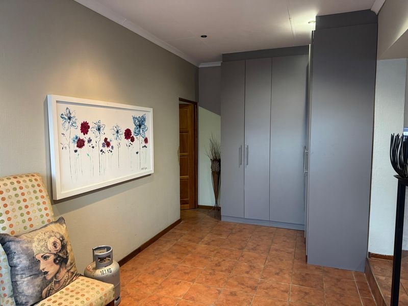 A functional hallway featuring modern grey built-in cupboards and durable tiled flooring, providing ample storage space and a clean, neutral aesthetic.