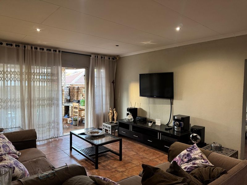 A comfortable living room featuring tiled flooring, recessed lighting, and a sliding glass door providing access to an outdoor patio area.