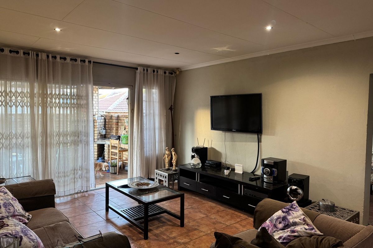 A comfortable living room featuring tiled flooring, recessed lighting, and a sliding glass door providing access to an outdoor patio area.