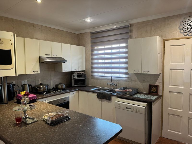 Functional kitchen featuring built-in cabinetry, laminate countertops, gas hob, extractor fan, and tiled backsplash with ample storage space.