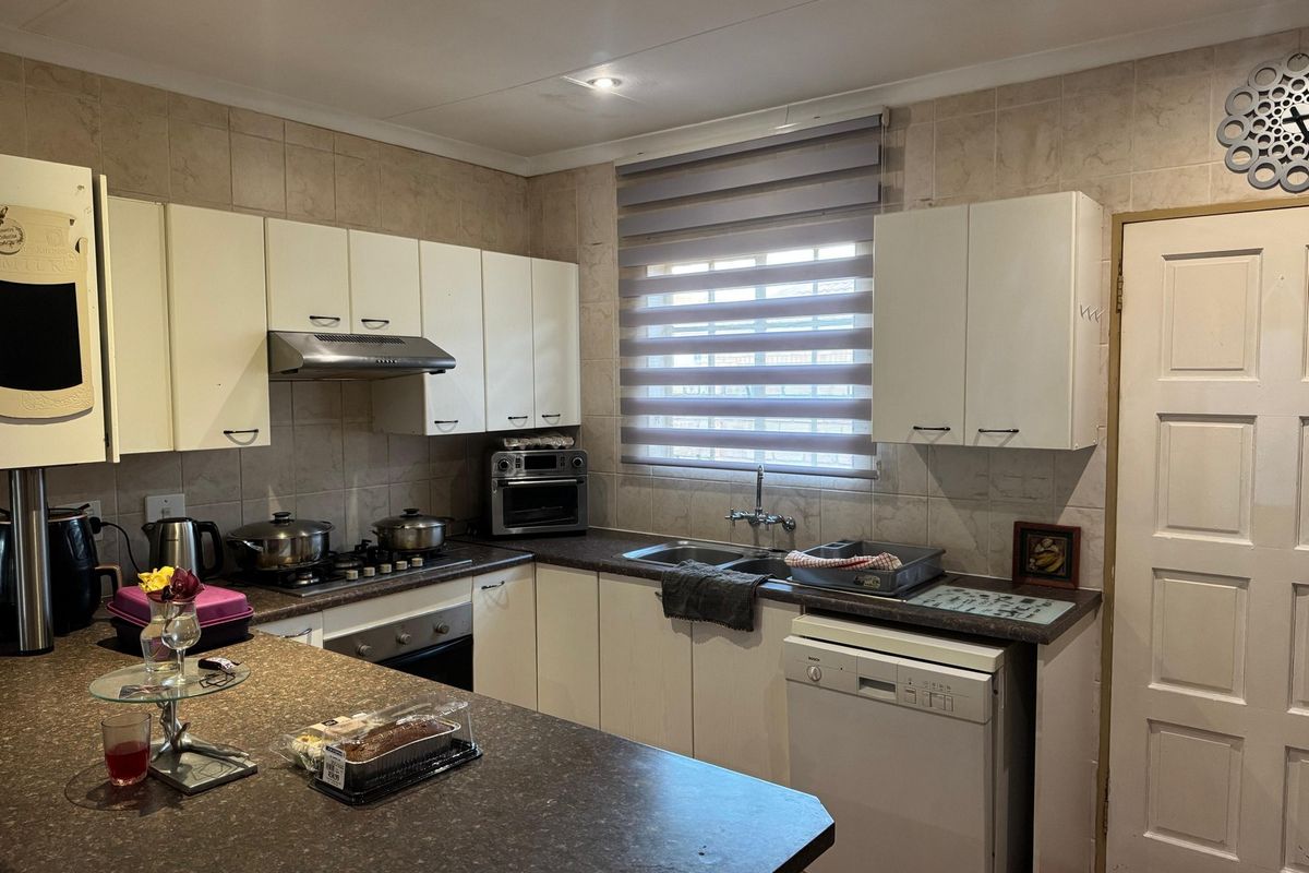 Functional kitchen featuring built-in cabinetry, laminate countertops, gas hob, extractor fan, and tiled backsplash with ample storage space.