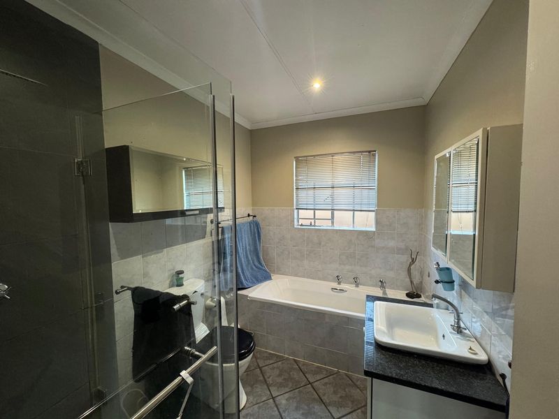 A functional bathroom featuring a glass-enclosed shower, a built-in bathtub, and a vanity with a granite countertop.