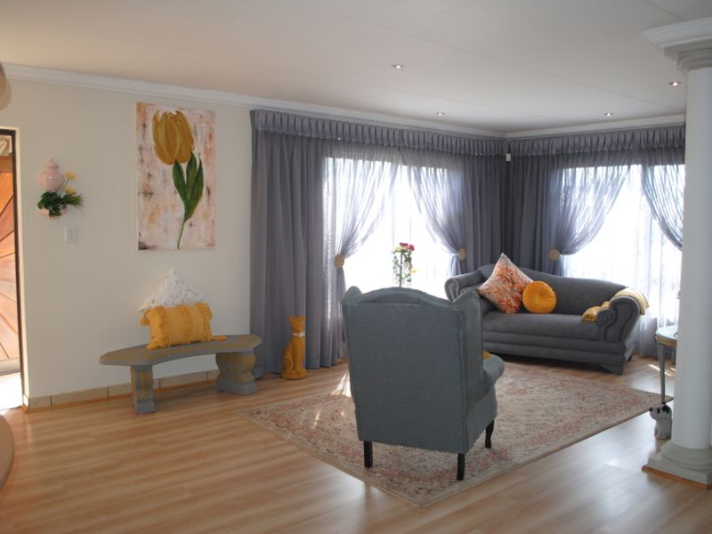 A bright living room featuring laminate flooring, recessed downlighting, and a decorative column, creating an open and inviting atmosphere.