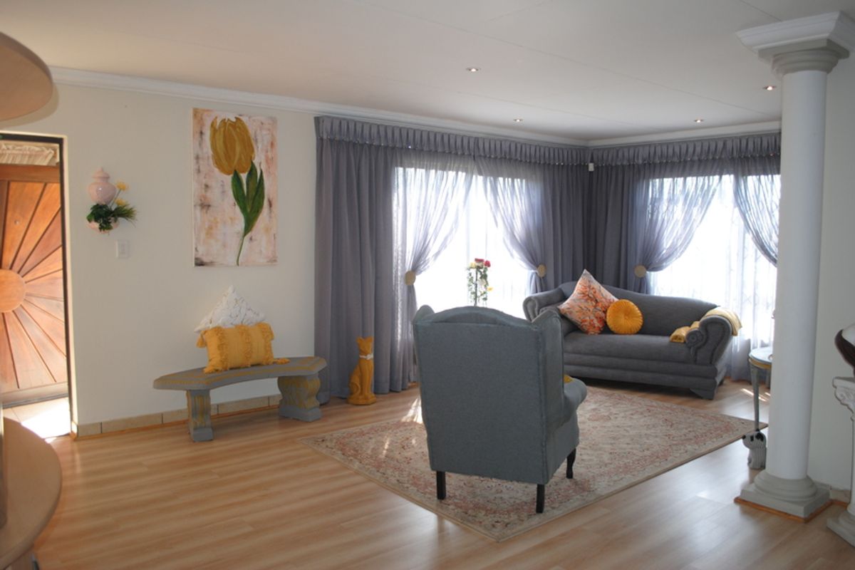 A bright living room featuring laminate flooring, recessed downlighting, and a decorative column, creating an open and inviting atmosphere.