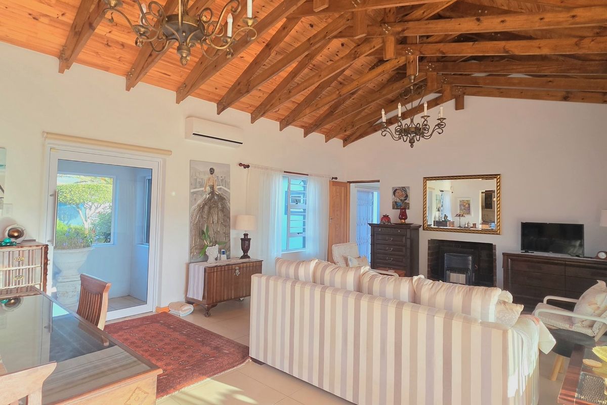 Spacious living area featuring high exposed timber beam ceilings, a cozy fireplace, and direct access to outdoor spaces through sliding glass doors.
