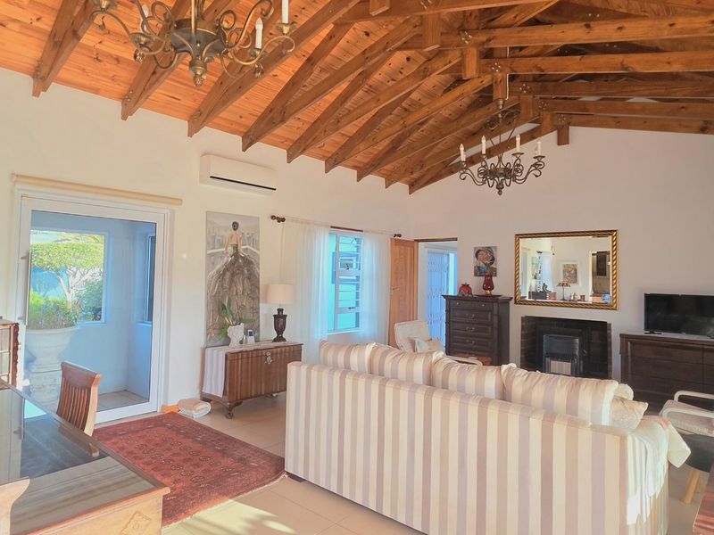 Spacious living area featuring high exposed timber beam ceilings, a cozy fireplace, and direct access to outdoor spaces through sliding glass doors.