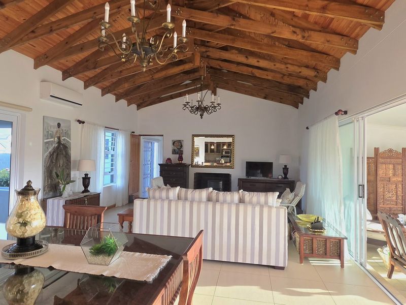 Spacious open-plan living area featuring high exposed timber rafter ceilings, tiled flooring, a fireplace, and large sliding glass doors leading to the outdoors.