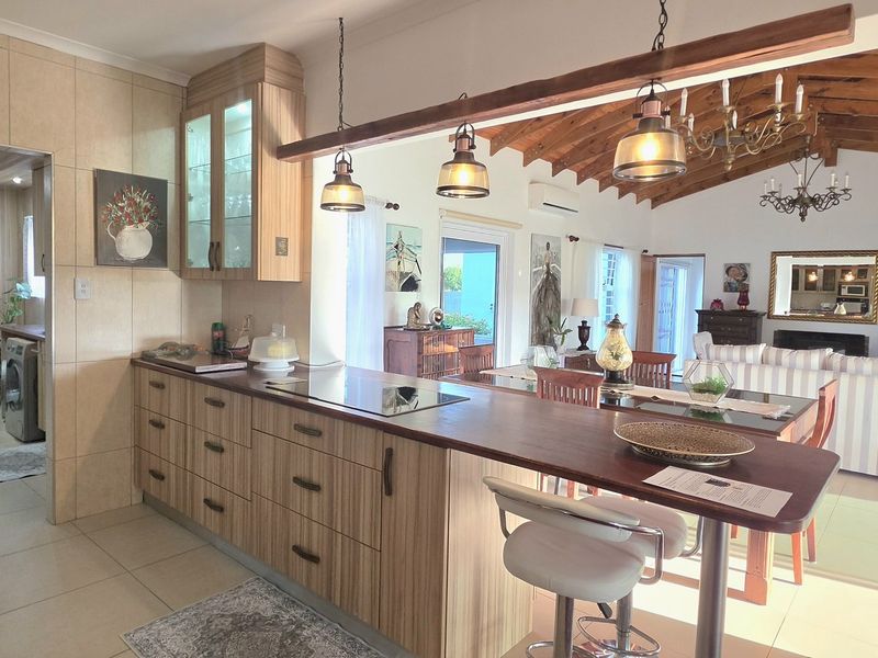 Spacious open-plan living and kitchen area featuring a breakfast bar, modern cabinetry, and high vaulted ceilings with exposed timber beams.