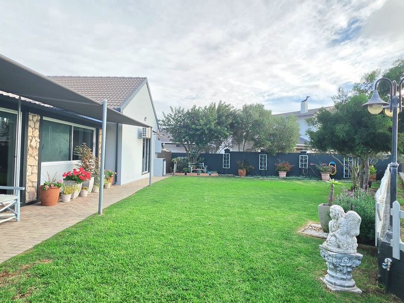 A well-maintained rear garden featuring a paved patio area, a lush green lawn, and secure boundary walls, providing a pleasant outdoor living space.