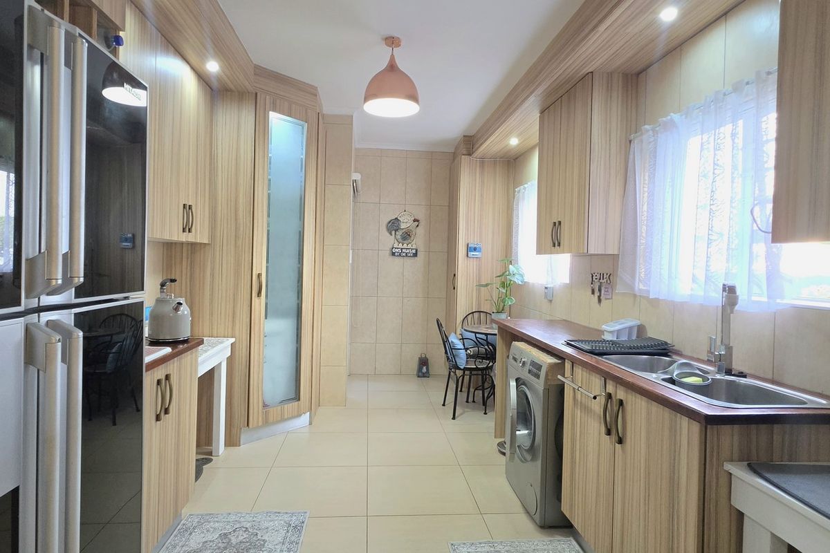 A well-maintained kitchen featuring extensive wood-grain cabinetry, tiled flooring, and integrated sink area with modern lighting fixtures.
