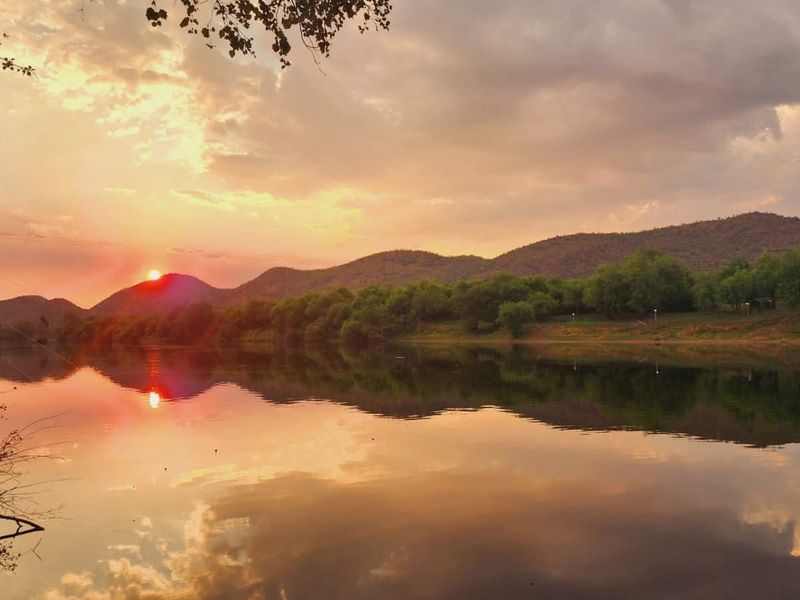 A scenic sunset view over a calm river with rolling hills in the background, showcasing the natural beauty of the property surroundings.