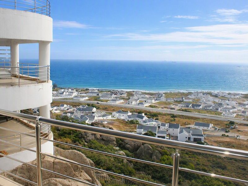 Elevated coastal view from a balcony featuring a modern stainless steel balustrade, overlooking the surrounding residential estate and ocean.