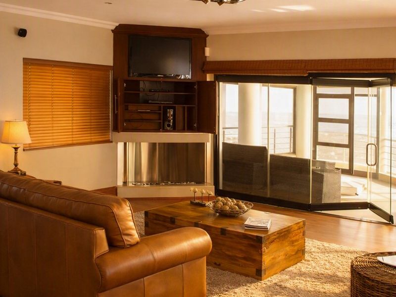 A comfortable living room featuring timber flooring, a built-in fireplace with integrated cabinetry, and large sliding glass doors opening to an outdoor area.