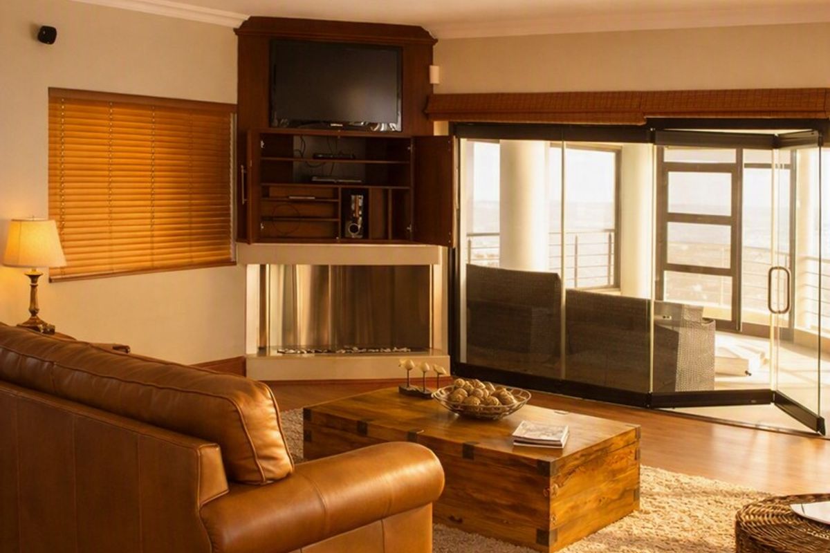 A comfortable living room featuring timber flooring, a built-in fireplace with integrated cabinetry, and large sliding glass doors opening to an outdoor area.