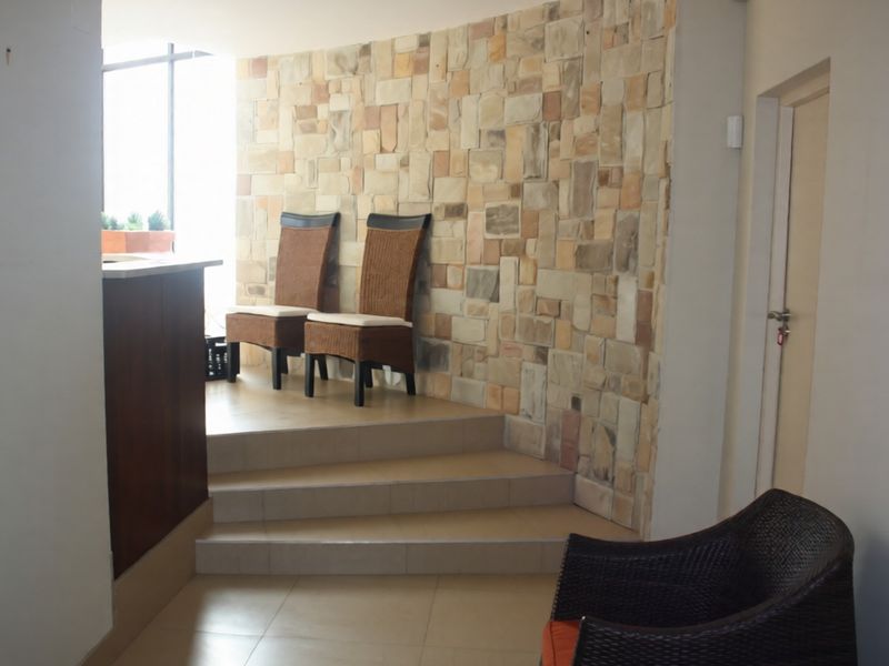 Living area featuring a curved stone accent wall, raised platform, and tiled flooring, creating a distinct architectural focal point.