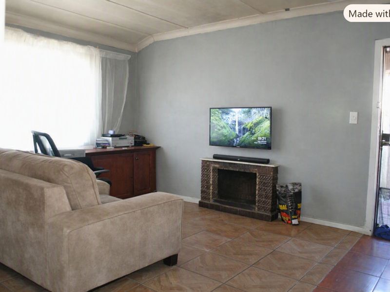 A living room featuring tiled flooring and a built-in fireplace, with direct access to an exterior area through a security gate.