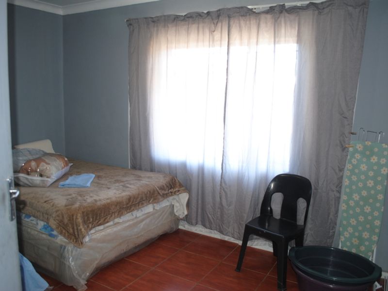 A bedroom featuring tiled flooring and neutral wall paint, providing a functional space with natural light through the window.