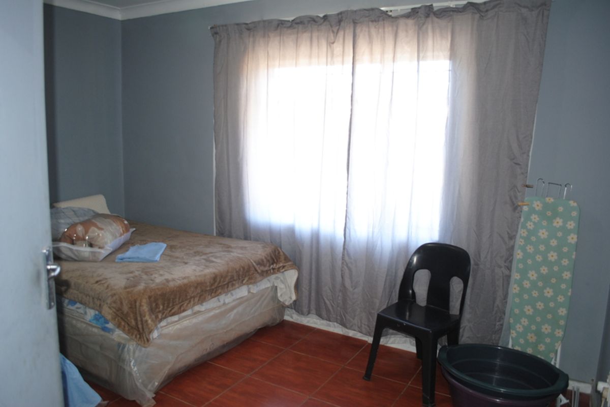 A bedroom featuring tiled flooring and neutral wall paint, providing a functional space with natural light through the window.