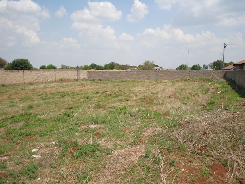 A vacant residential plot featuring perimeter brick walling and natural grass coverage, suitable for future development.