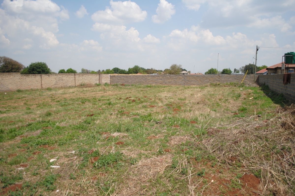 A vacant residential plot featuring perimeter brick walling and natural grass coverage, suitable for future development.