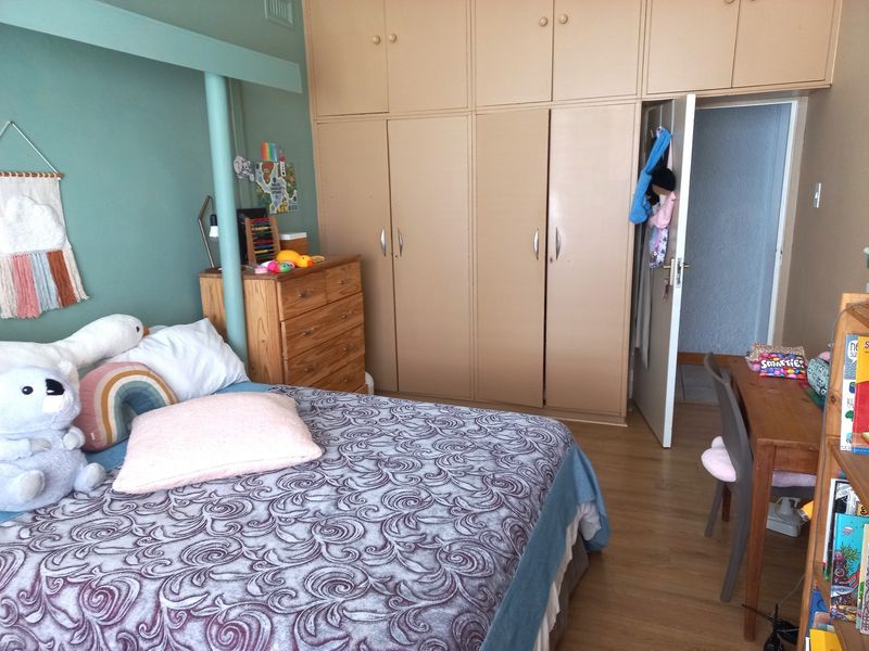 A bedroom featuring built-in cupboards and laminate flooring, offering functional storage space.