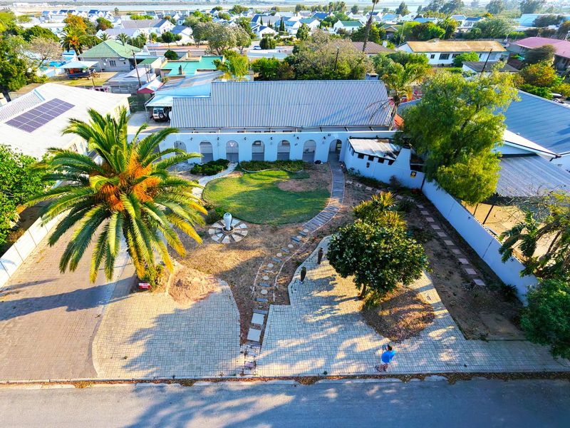 Aerial view of a residential property featuring a paved driveway, landscaped garden with a central lawn, and a building with an arched facade.