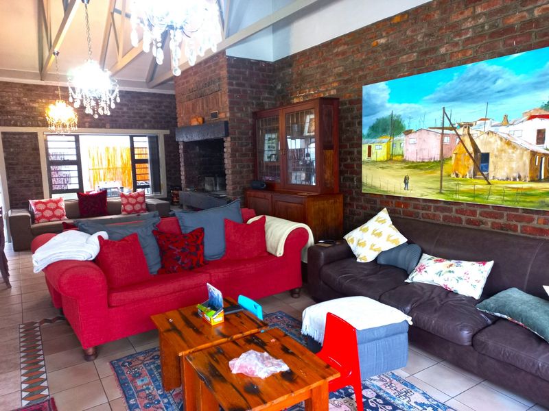 Spacious living room featuring exposed brick walls, a vaulted ceiling with timber beams, and a large built-in fireplace.